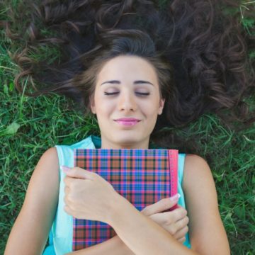 jente med bok, ligger i gresset